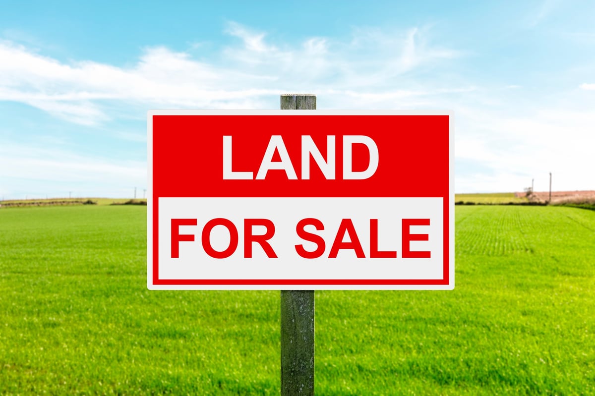 Land for sale sign in green grass