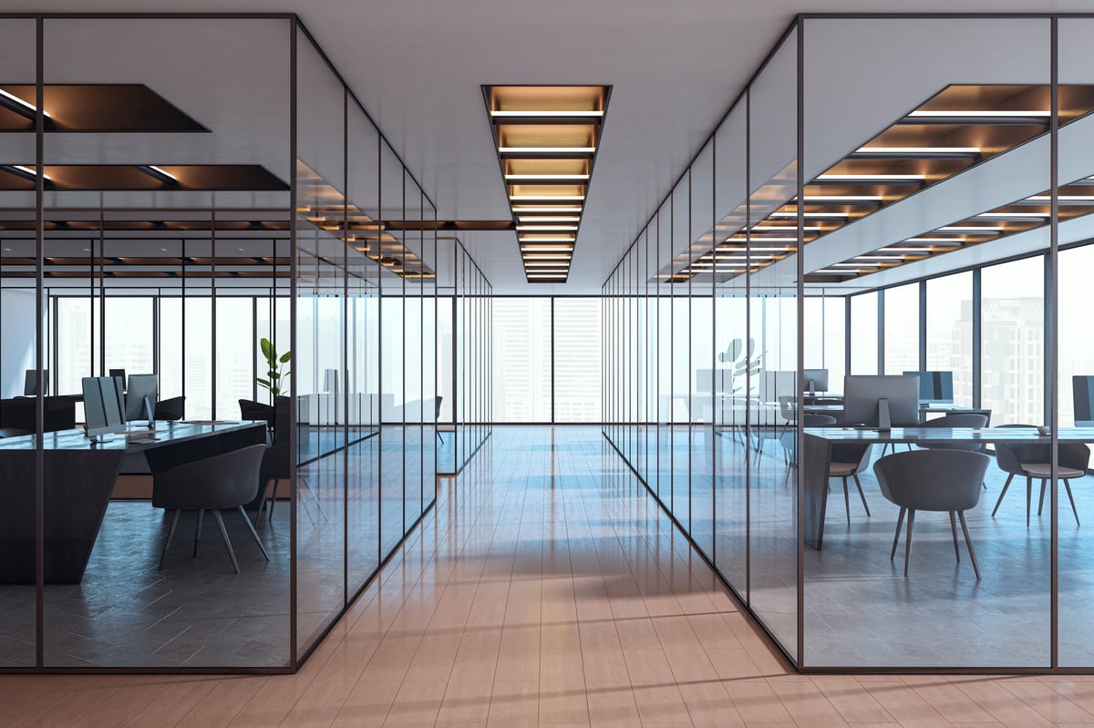 Contemporary empty office interior with glass partitions, stylish furniture and city view in background