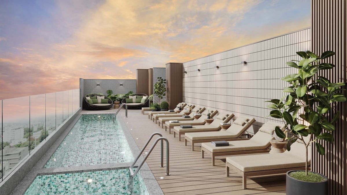 Luxury rooftop pool deck with lounge chairs, modern building, and sunset sky view