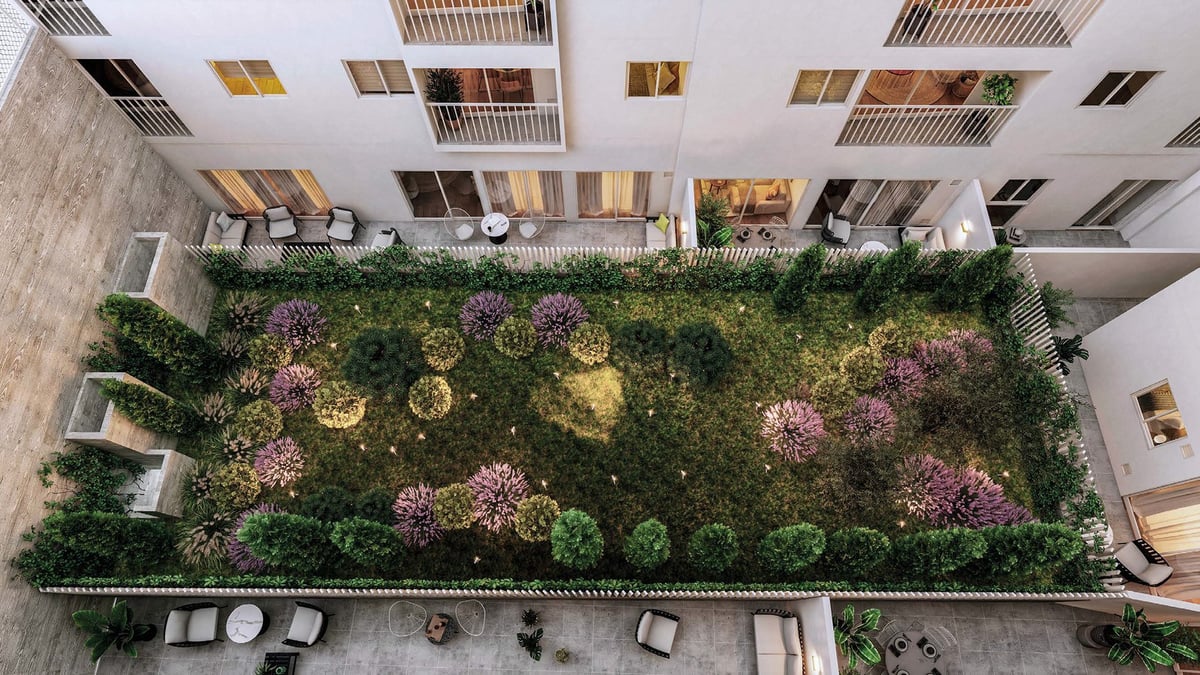 Overhead view of a rooftop garden with pink flowering plants, green foliage, and scattered seating areas bordered by buildings