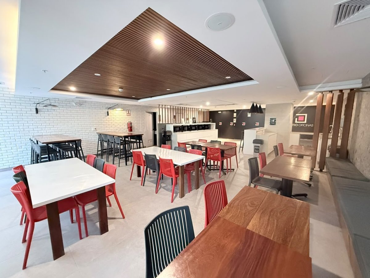 Modern restaurant dining area with white tables, red chairs, wooden ceiling accent, and contemporary lighting