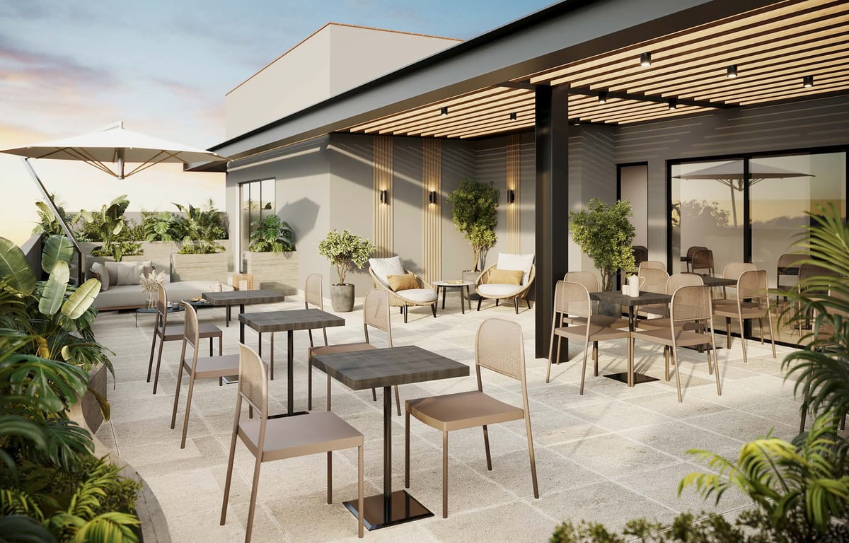 Modern rooftop terrace with dining tables, comfortable seating, potted plants, overhead lighting, and a covered pergola structure overlooking the city skyline.