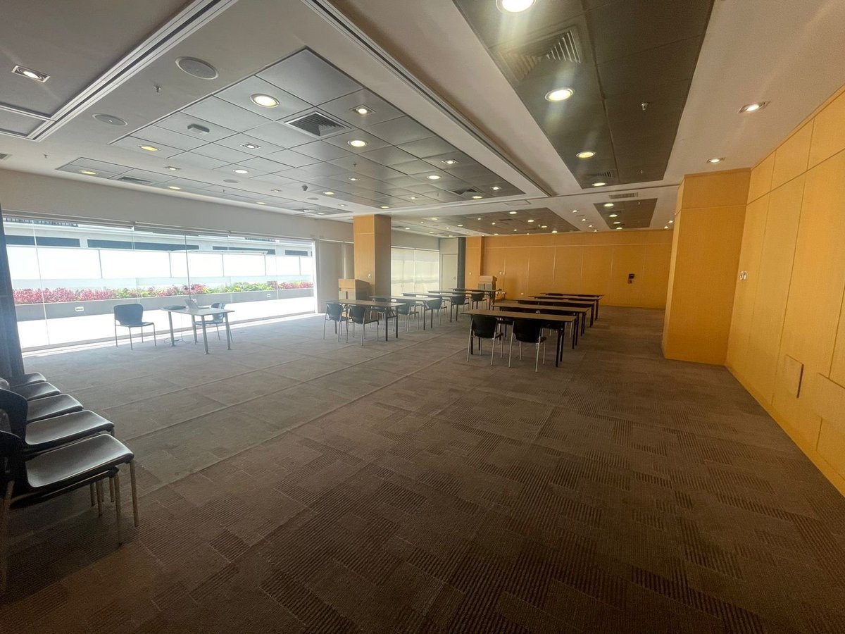 Modern office or conference space with yellow walls, brown flooring, and extensive windows along one side