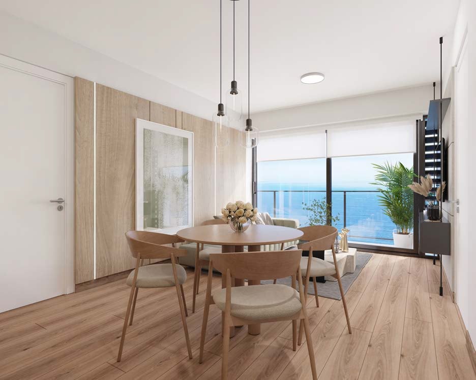 Modern dining room with wooden table and chairs, pendant lights, and ocean view through large windows