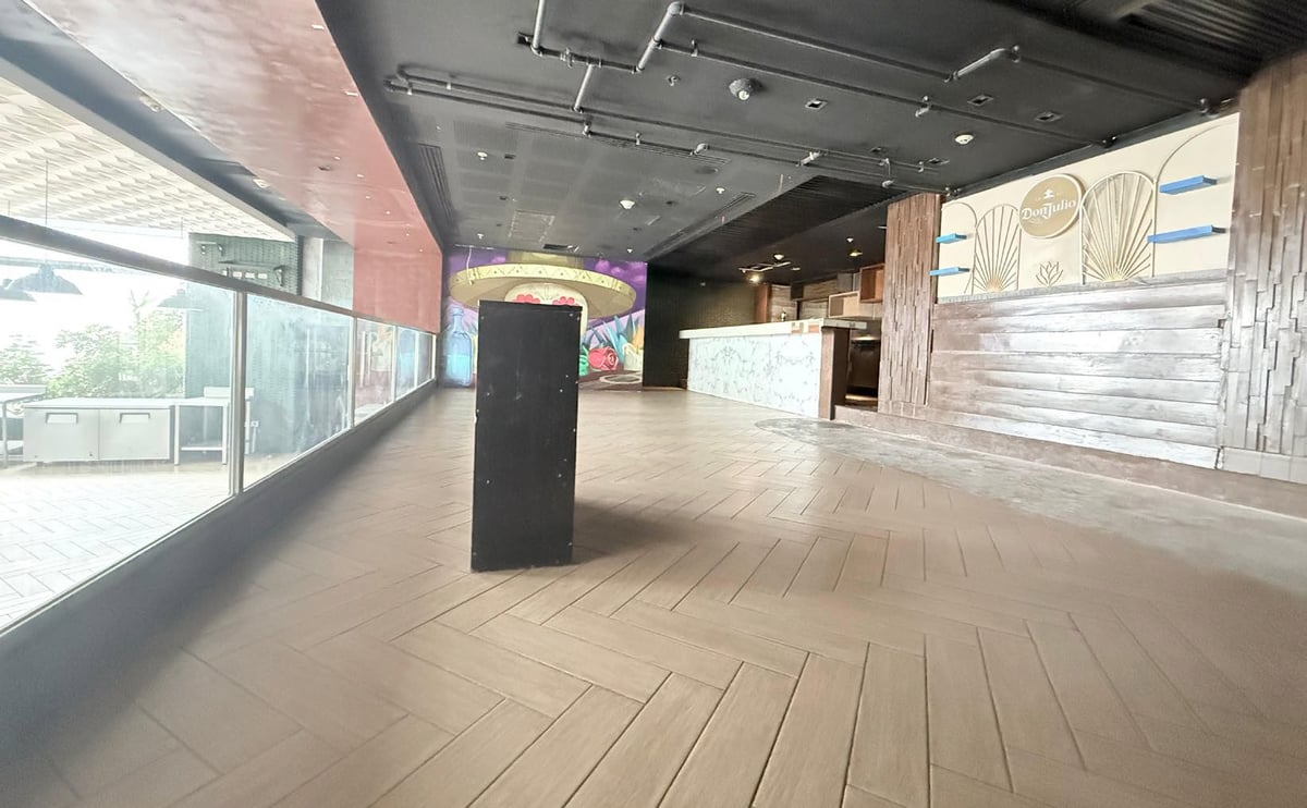 Empty modern retail or commercial space with polished wood flooring, floor-to-ceiling windows, and contemporary fixtures