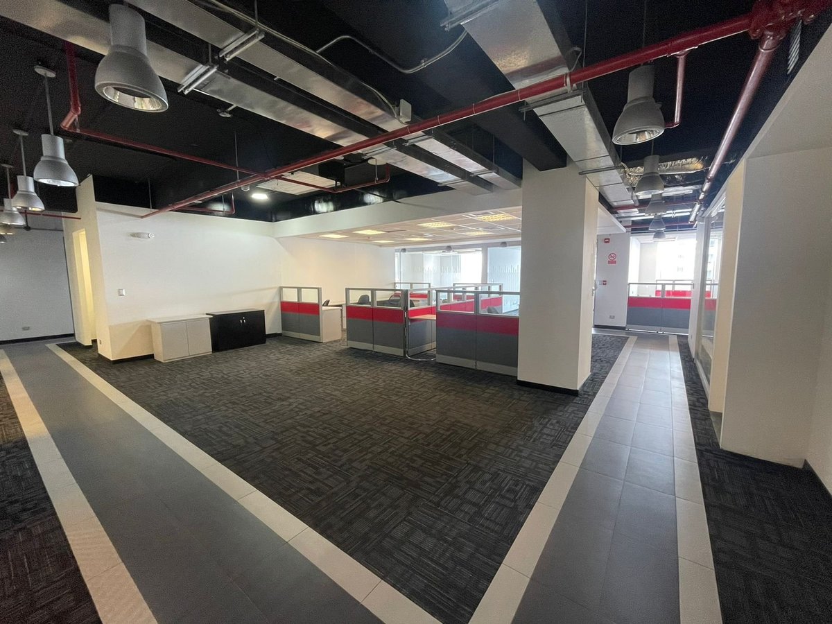 Empty modern office space with exposed red ductwork, concrete columns, and black and white flooring
