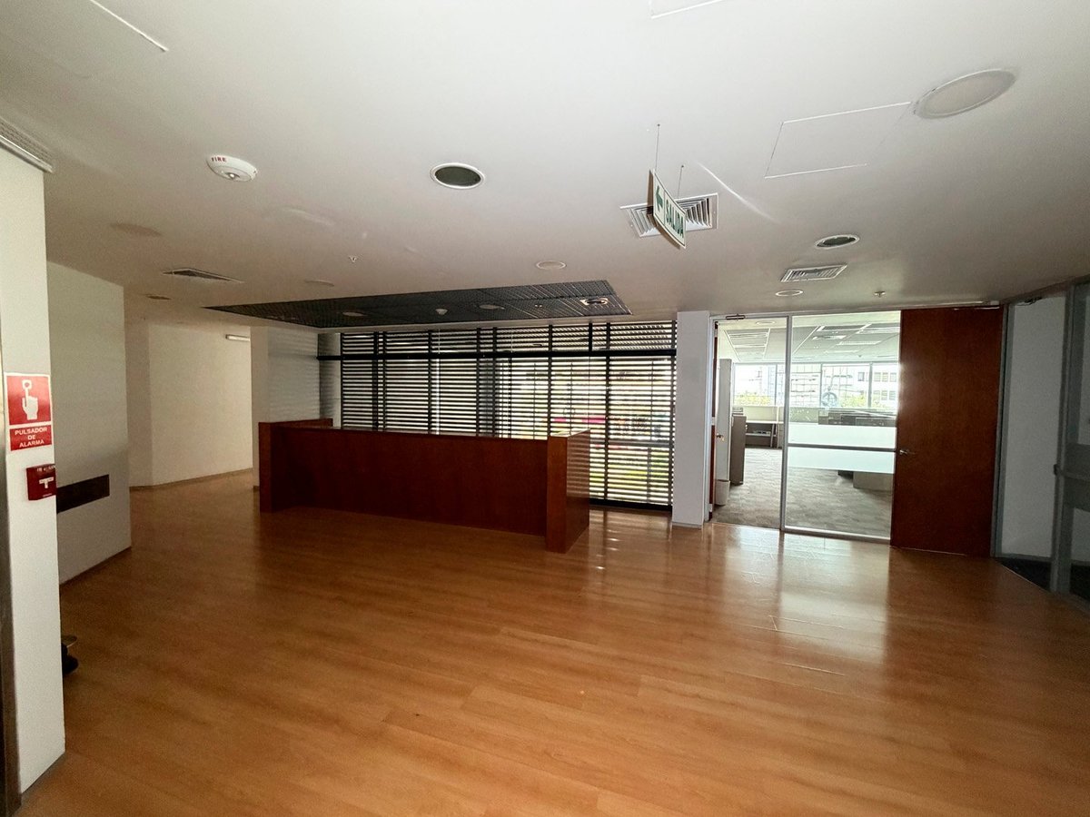 Empty modern office or retail space with wooden flooring, glass partitions, and contemporary furniture