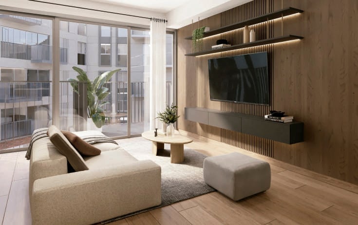 Modern living room with beige furniture, wall-mounted TV, wooden shelving, large windows, and hardwood floors