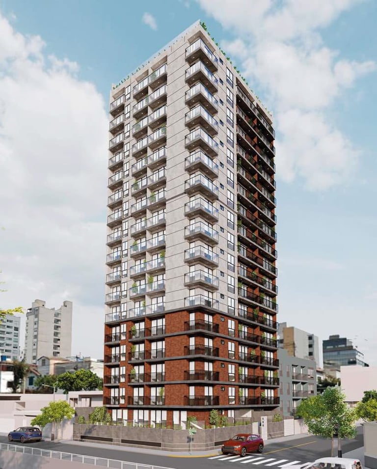 Tall residential building with brick base and concrete upper floors, featuring multiple balconies under blue sky with clouds