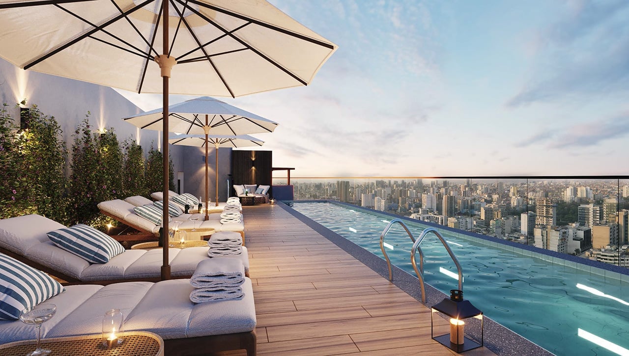 Luxury rooftop pool deck with sunbeds, umbrellas, and infinite pool overlooking a sprawling cityscape at sunset