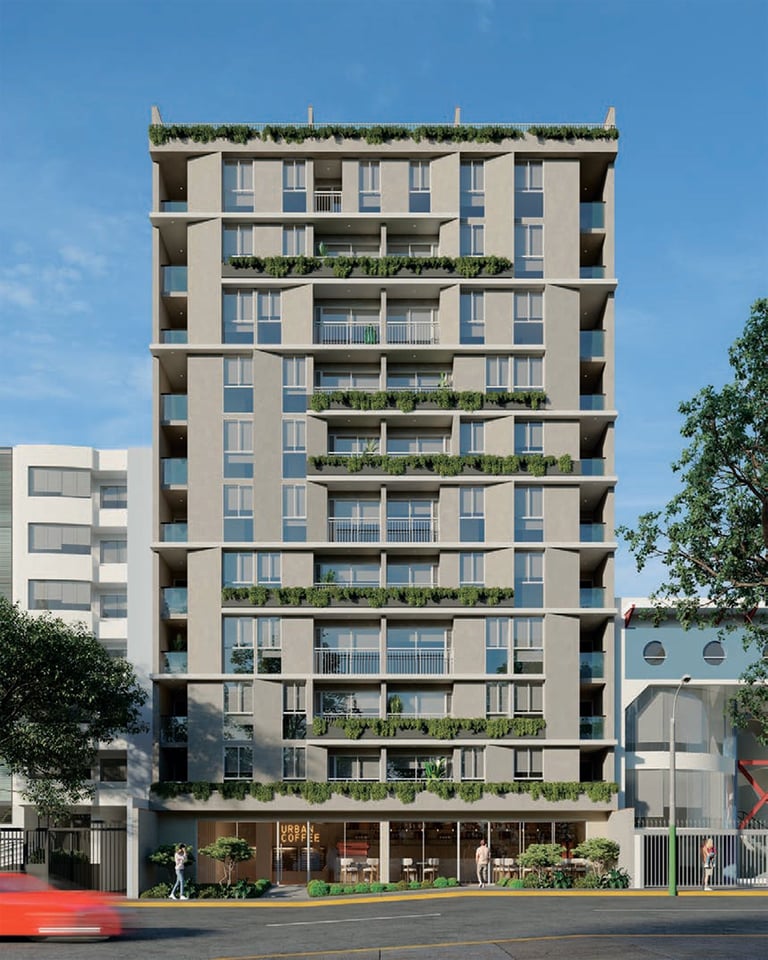 Modern residential building with nine stories, beige facade, balconies with greenery, ground-floor retail space, and clear blue sky background
