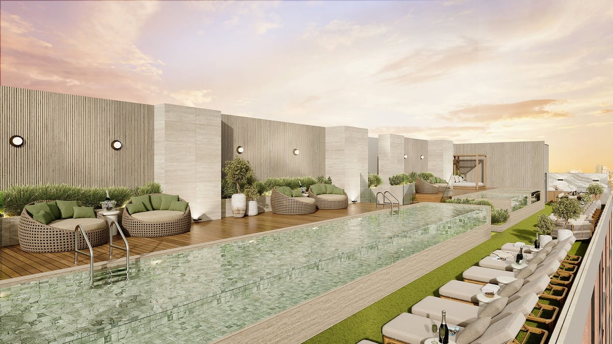 Modern rooftop pool area with lounge seating, white umbrellas, and greenery overlooking a city skyline at sunset