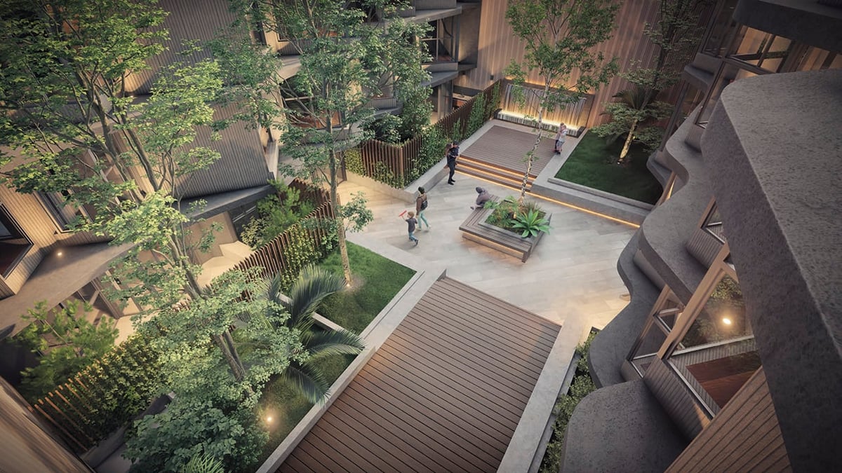 Aerial view of a modern courtyard with wooden deck, planted gardens, and residential buildings at dusk