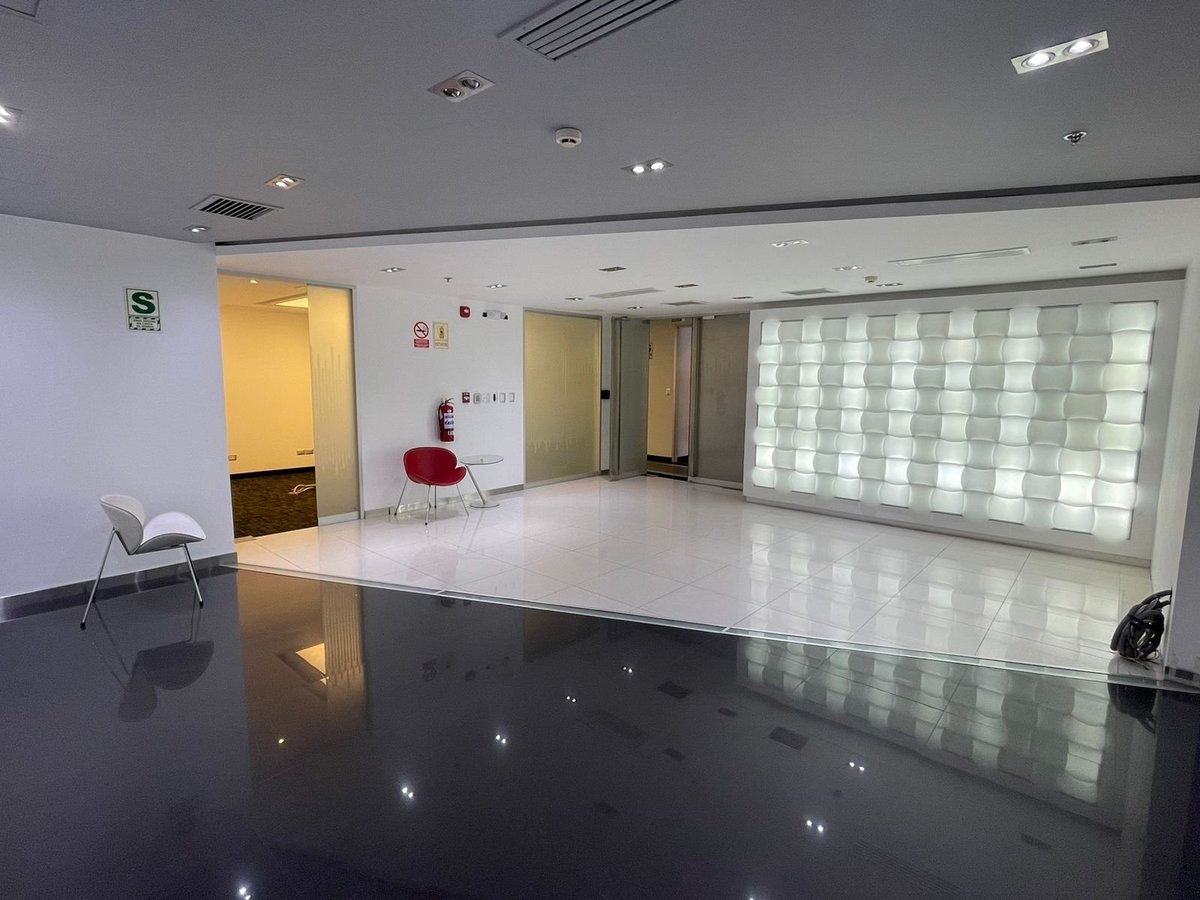 Modern empty office or retail space with polished black floor, white walls, glass block feature wall, and minimalist furniture