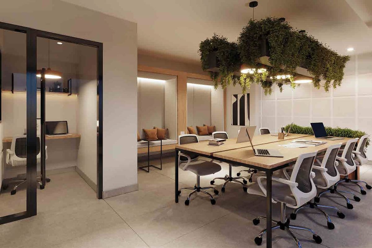 Modern office workspace with wooden table, ergonomic chairs, glass-partitioned meeting room, and hanging greenery in ceiling