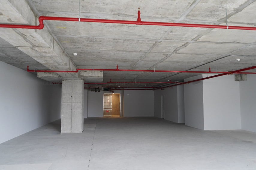 Empty concrete commercial or warehouse space with red pipes on ceiling and support columns