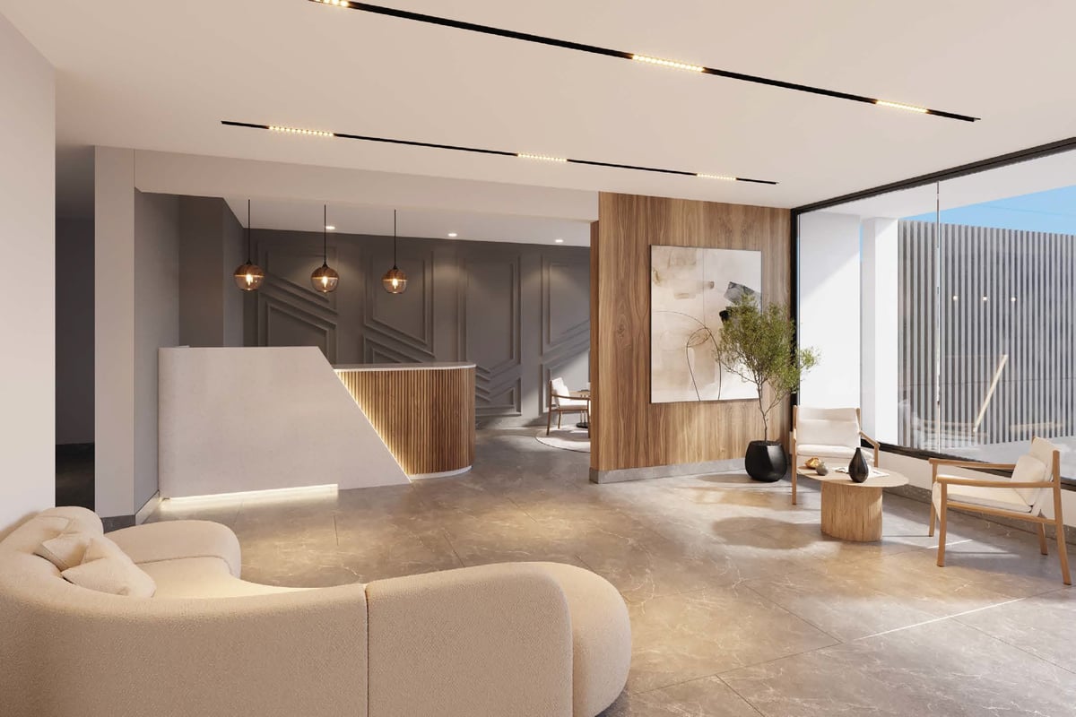 Modern office lobby with curved beige seating, wooden reception desk, pendant lighting, and floor-to-ceiling windows overlooking a city