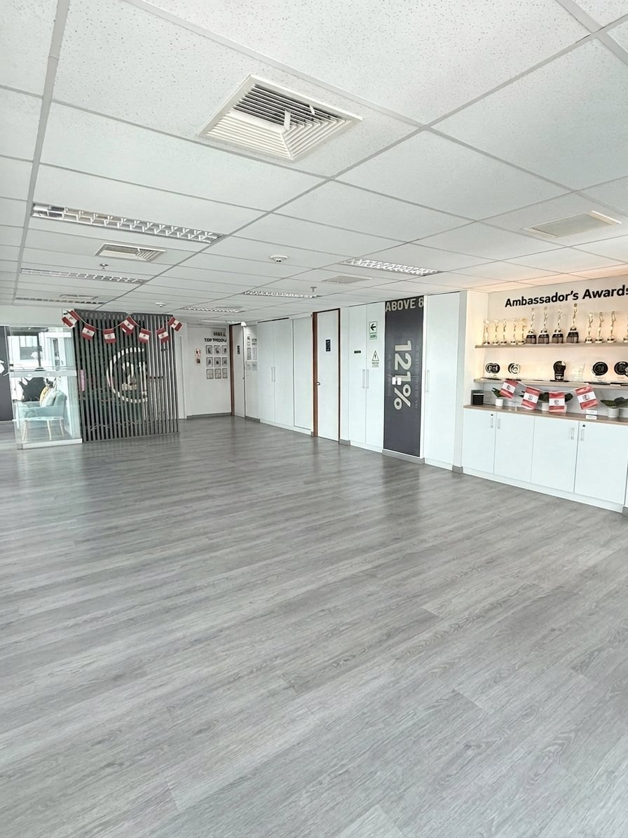 Espacio moderno de oficina o retail vacío con piso gris claro, cielo raso blanco, displays en pared y mostrador a la derecha
