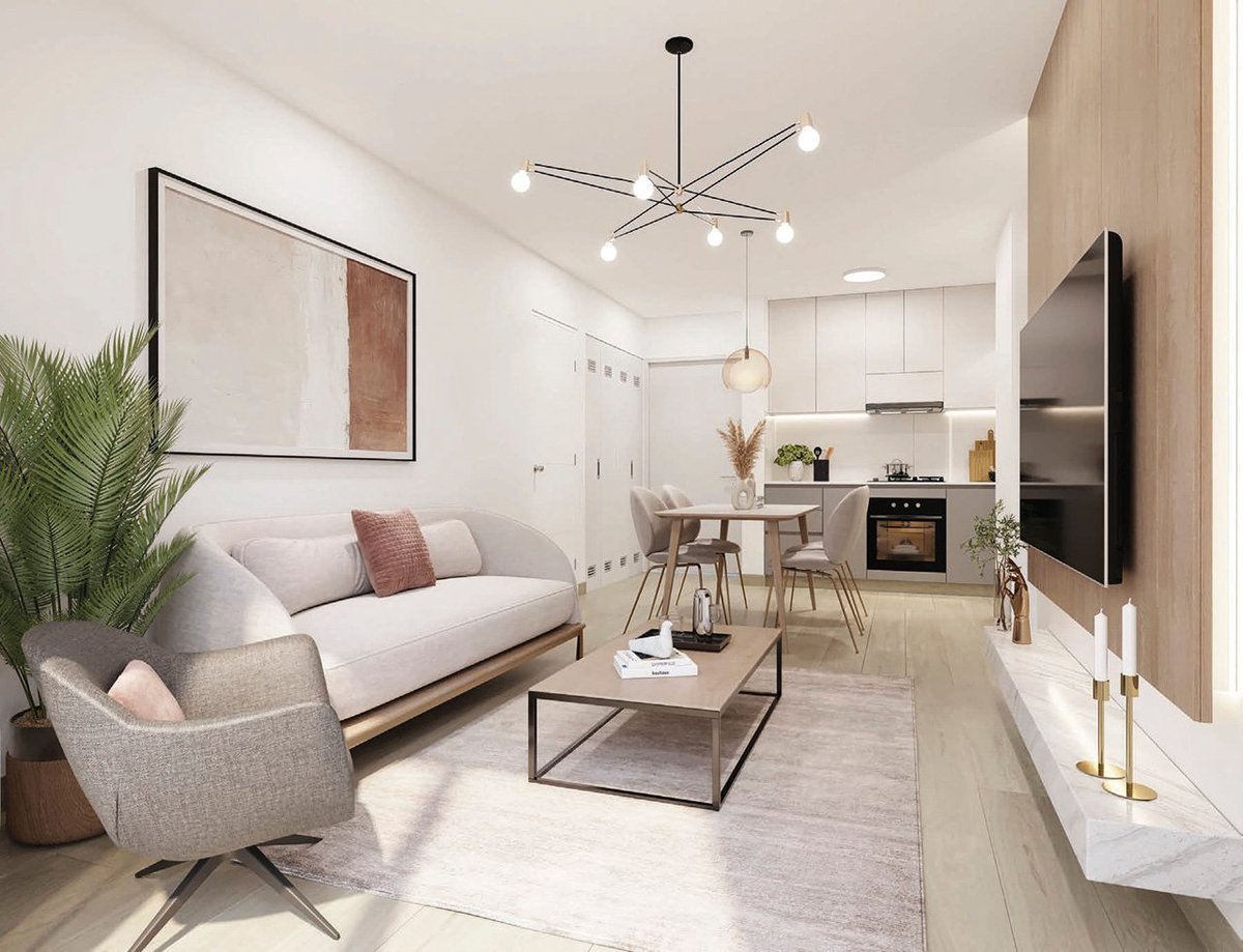 Modern open-plan apartment interior with light gray sofa, accent chair, coffee table, and kitchen area with dining table in neutral tones