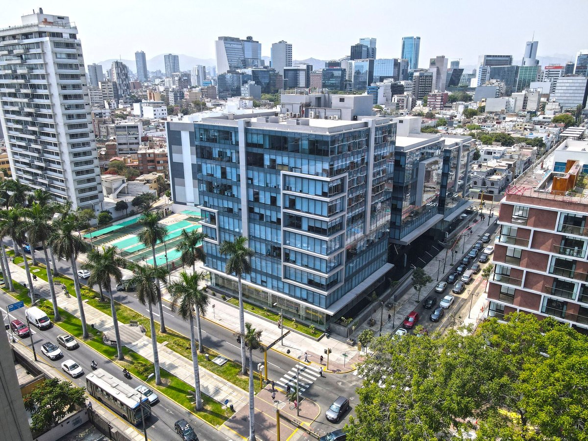 Modern high-rise residential building with pool and courtyard overlooking downtown cityscape with palm trees lining the street