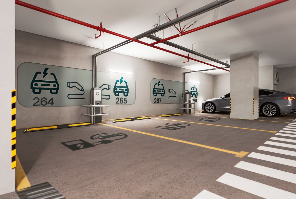 Modern electric vehicle charging station in underground parking garage with red pipes, yellow safety markings, and EV charging icons on the wall