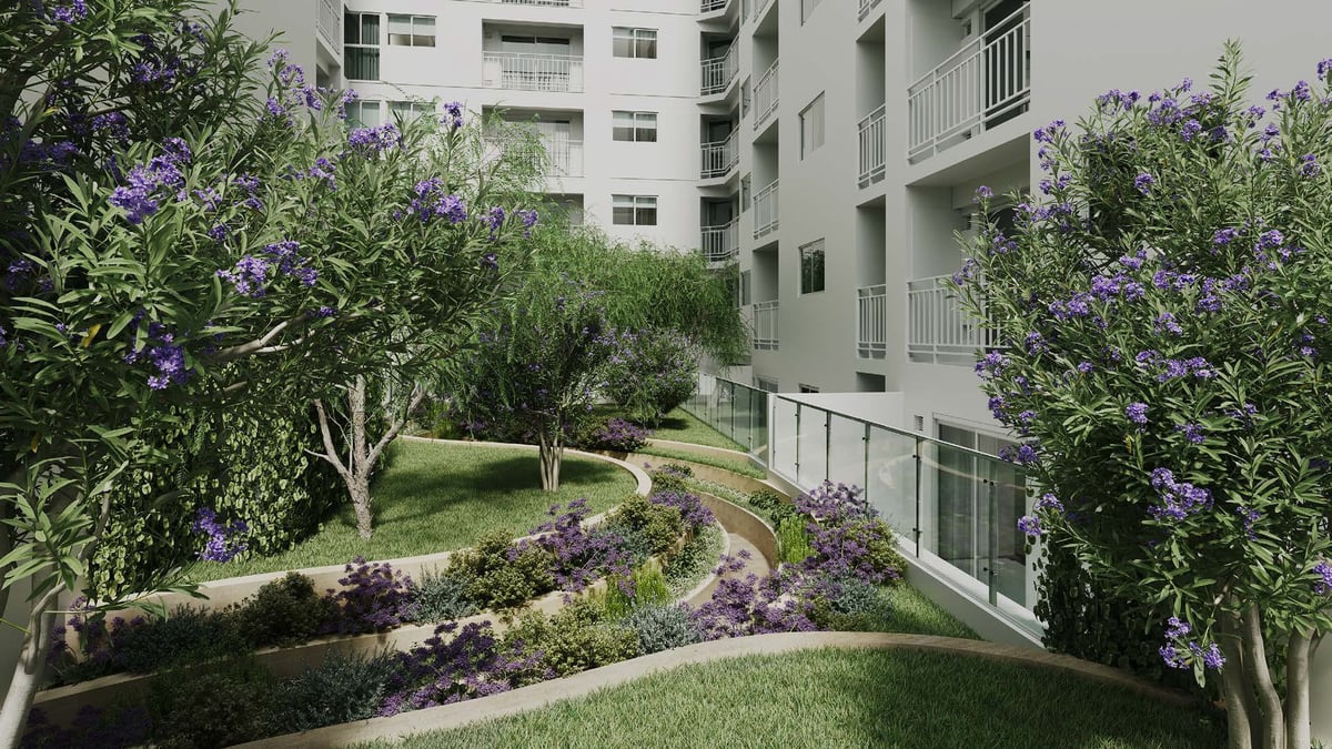 Modern apartment building courtyard with landscaped gardens, purple flowering shrubs, and green lawn areas