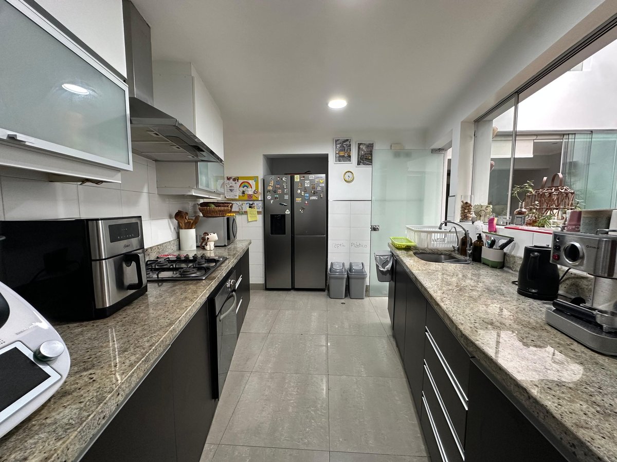Modern kitchen with black cabinets, granite countertops, stainless steel appliances, and natural lighting from windows