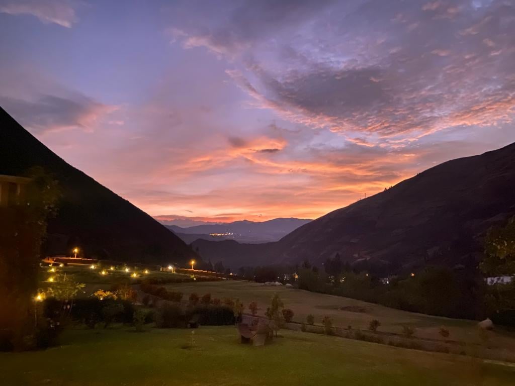 Twilight mountain valley with illuminated buildings and dramatic pink-orange sunset sky