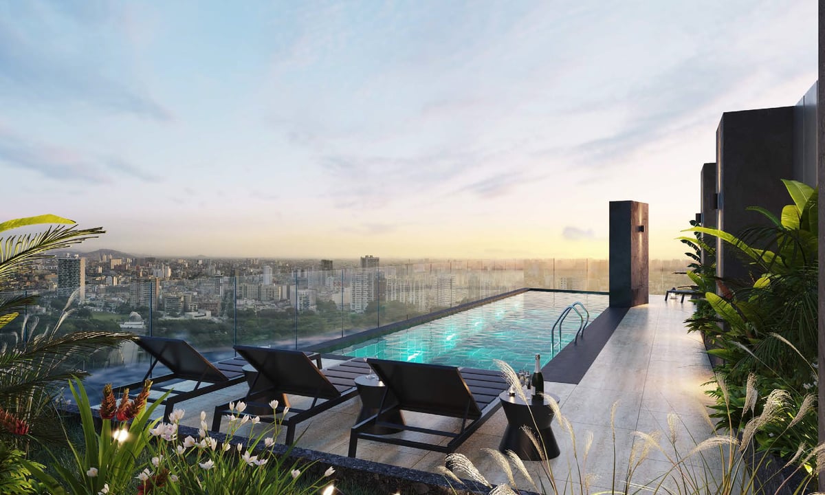 Rooftop infinity pool with lounge chairs overlooking a sprawling city skyline at sunset