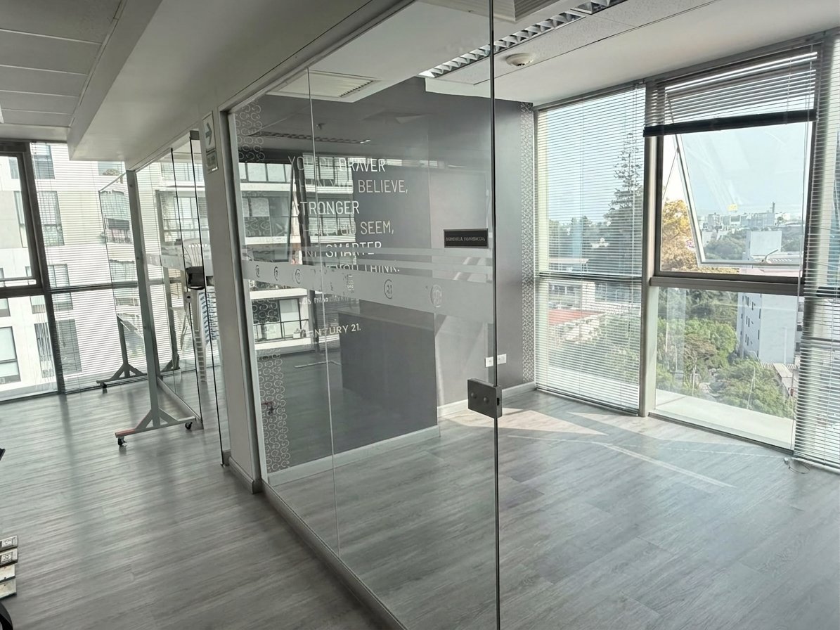 Espacio de oficina moderna con paredes y puertas de vidrio, piso de madera y grandes ventanales con vista al skyline de la ciudad