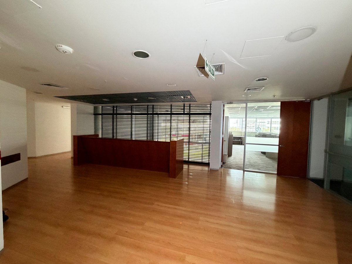 Empty office interior with wooden flooring, reception desk, glass partitions, and recessed ceiling lights