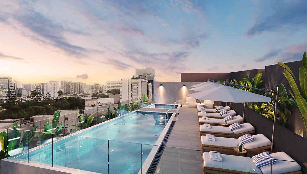 Rooftop swimming pool with loungers overlooking a city skyline at sunset