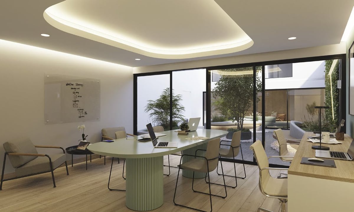 Modern office interior with glass desk, ergonomic chairs, bright LED ceiling lighting, and large windows overlooking outdoor courtyard.