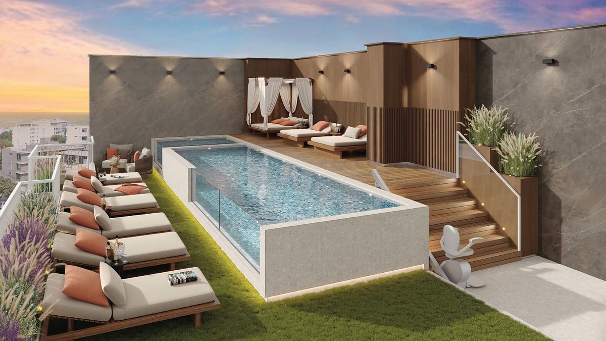 Luxury rooftop pool with lounge chairs, wooden deck, modern seating area, and city skyline at sunset