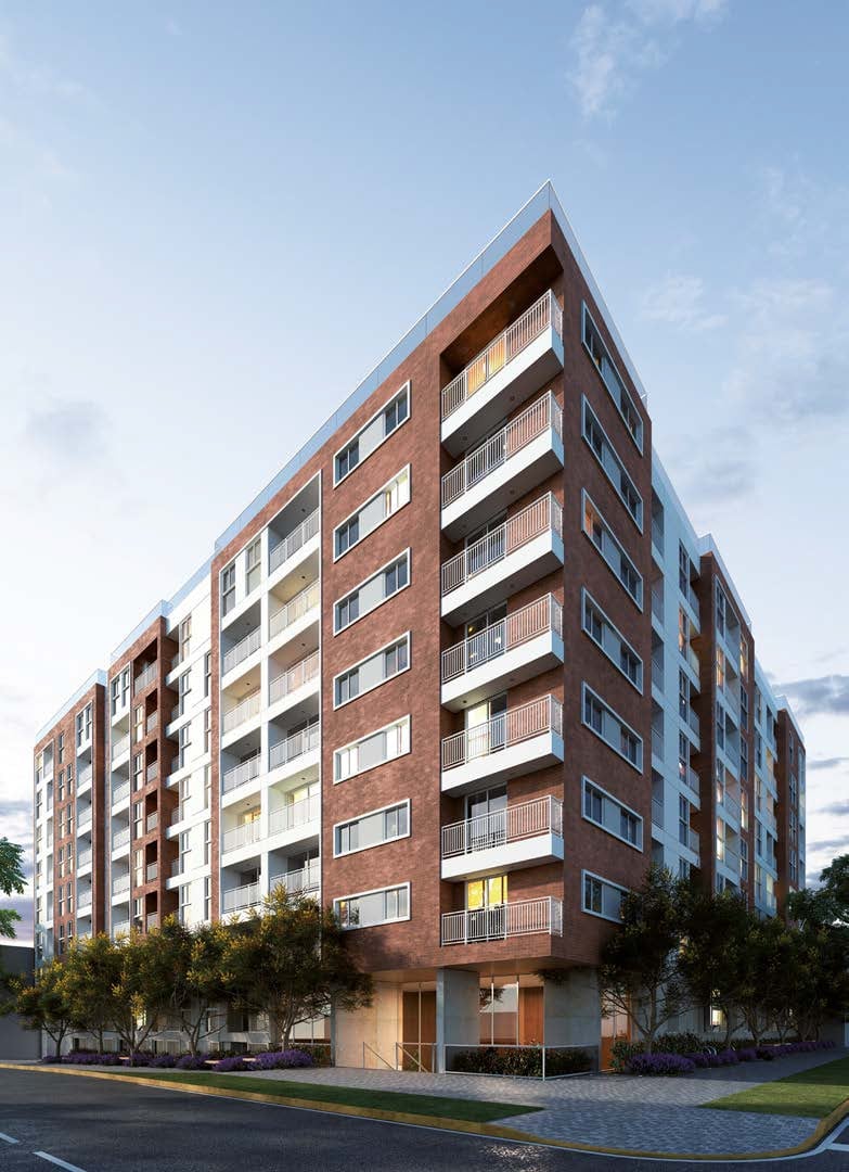 Modern brick residential apartment building with multiple balconies, ground floor retail space, and surrounding landscaping under blue sky