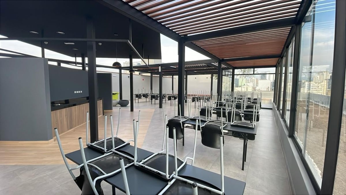 Modern office break room with black chairs, wooden reception area, and floor-to-ceiling windows overlooking a city skyline