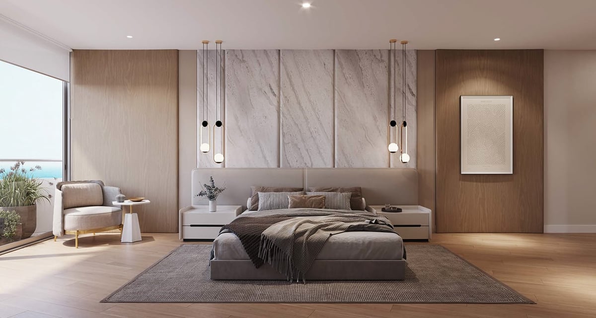 Modern bedroom with gray platform bed, marble wall feature, pendant lights, wooden accents, and lounge seating by window