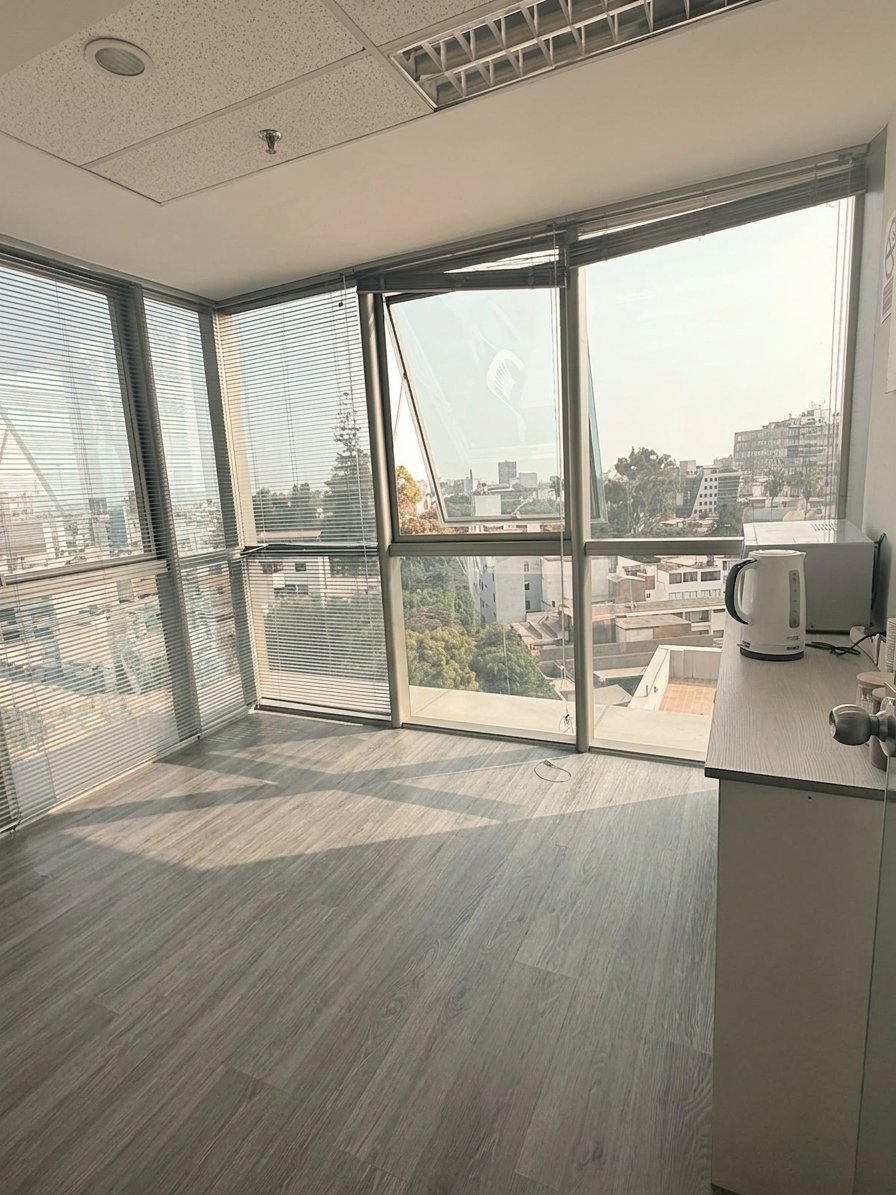Espacio de oficina en torre moderna con ventanales de piso a techo con vista a la ciudad, piso de madera y mobiliario mínimo