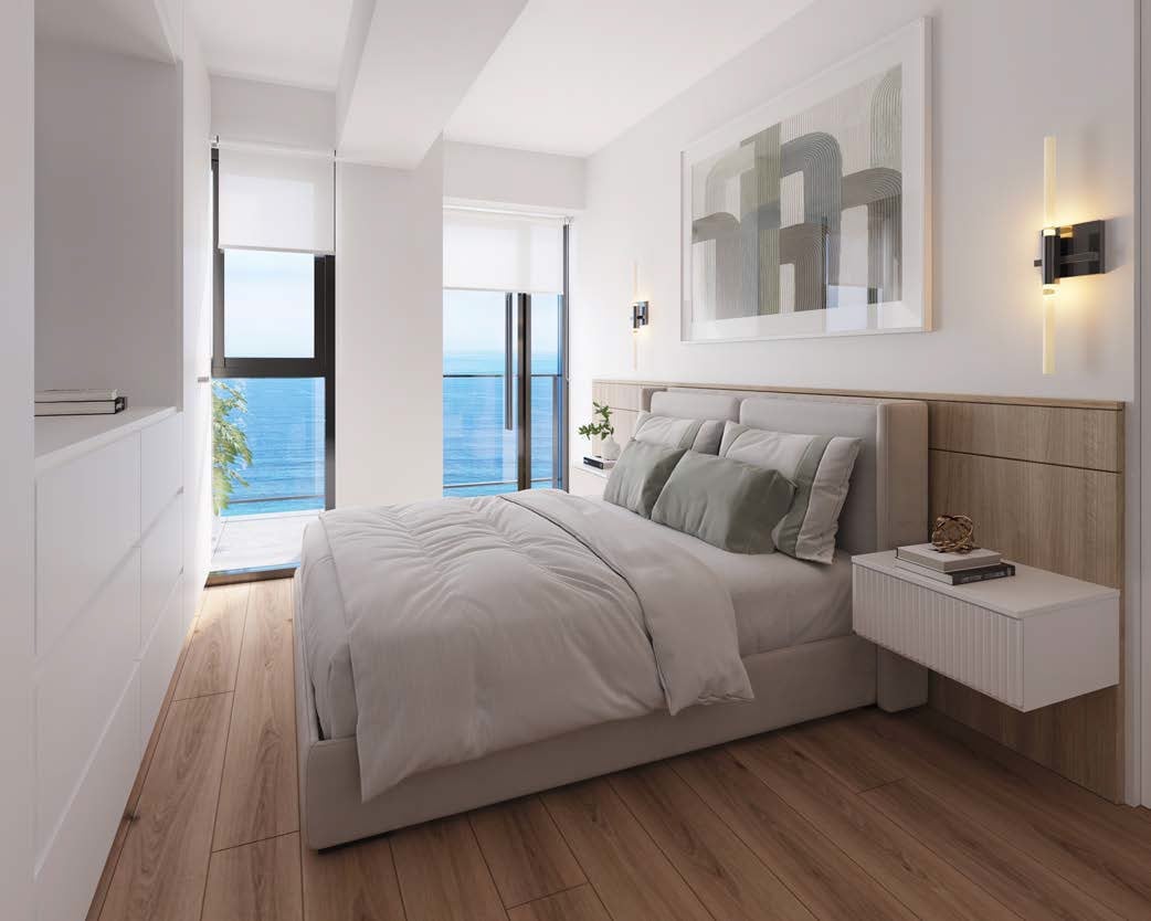 Modern bedroom with ocean view, gray upholstered bed, wooden flooring, white nightstand, and wall art
