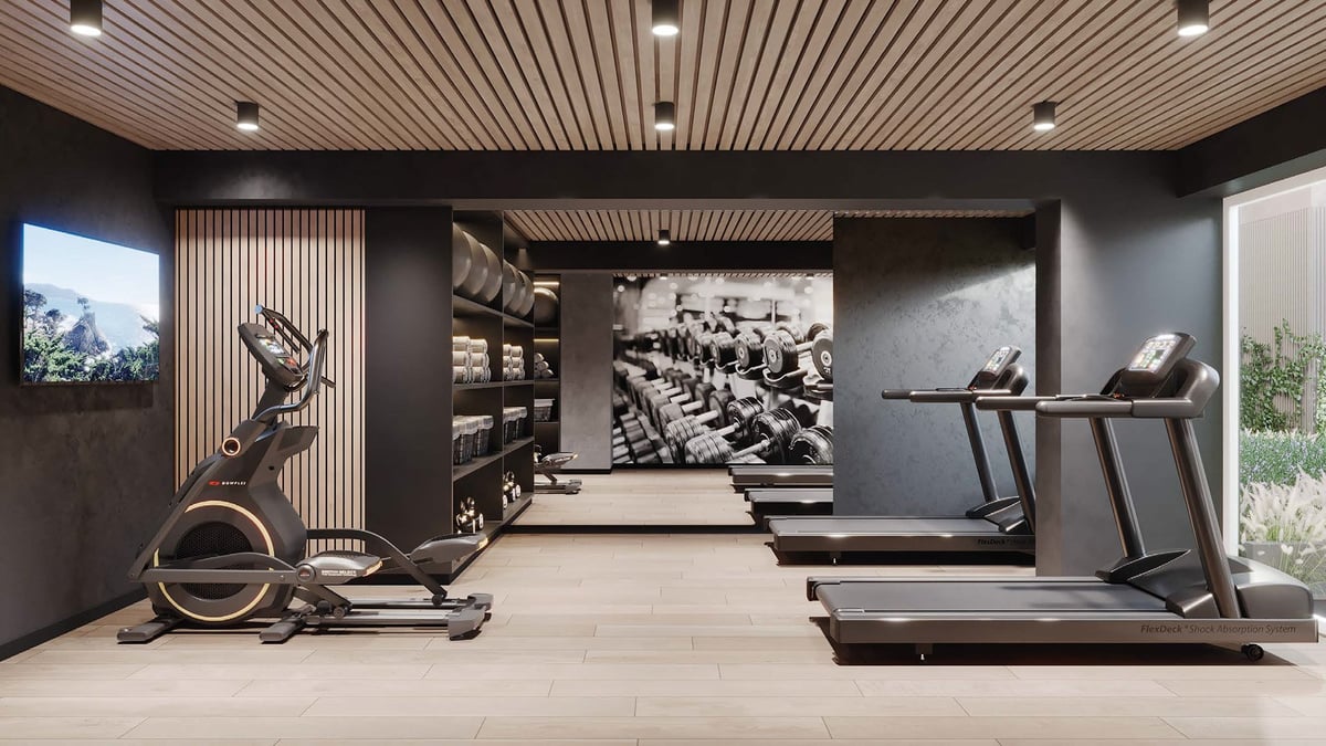 Modern gym interior with stationary bikes, treadmills, and exercise equipment under industrial ceiling with recessed lighting