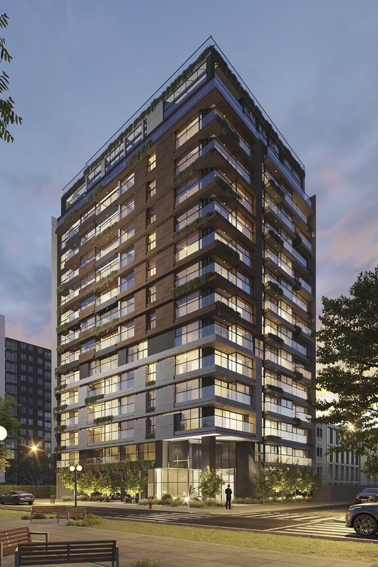 Modern multi-story residential building with illuminated windows at dusk, featuring a contemporary design with ground-level entrance and surrounding landscaping